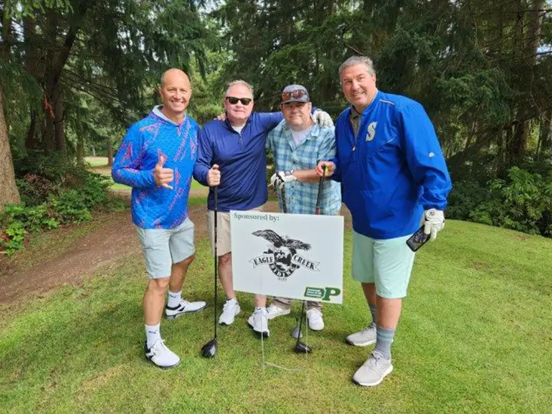 Golfers in front of sign from a sponsor